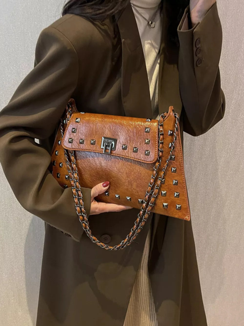 Brown embellished chain flap shoulder bag with silver studs and a turn-lock closure.