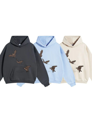 Embroidered flight hoodie in dark gray, light blue, and khaki with bird graphic. Relaxed fit.