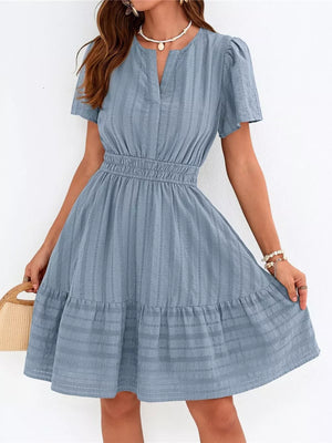 Light blue textured V-neck tiered dress with smocked waist and short sleeves.