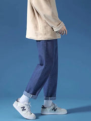 Dark blue relaxed-fit straight-leg jeans with cuffed hems, styled with white socks and sneakers.