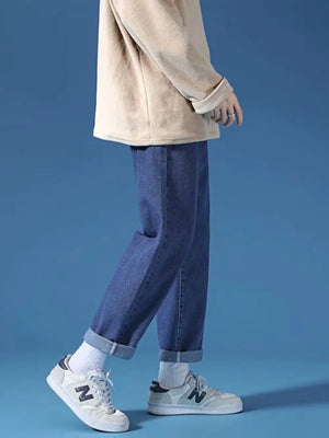 Dark blue relaxed-fit straight-leg jeans with cuffed hems, styled with white socks and sneakers.
