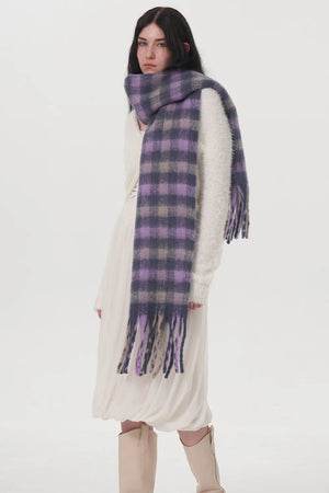 Plush lilac checkered scarf with fringe detail, worn by a woman.