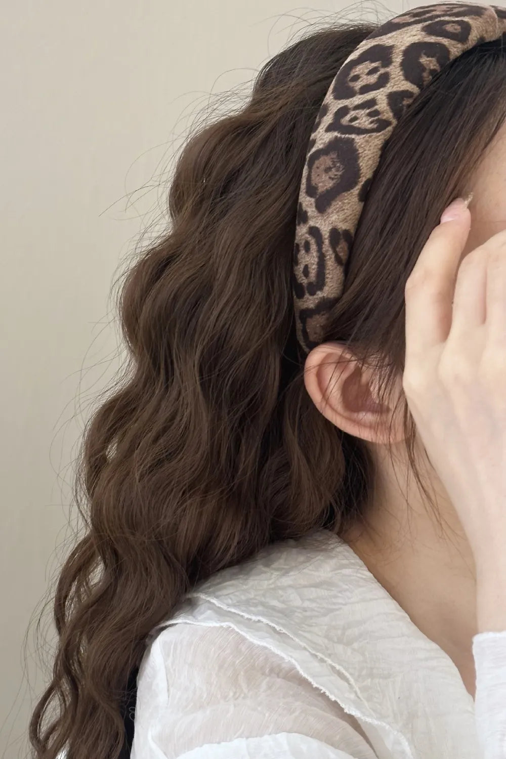Leopard print knotted headband with a bold design, styled with wavy brown hair.