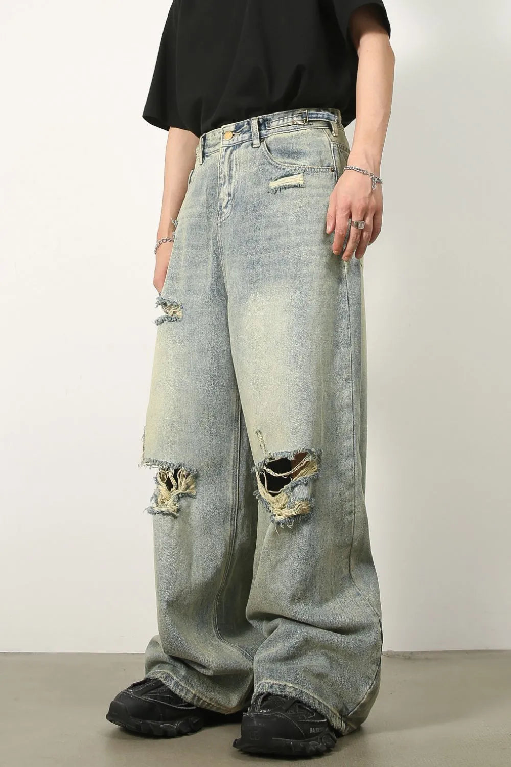 Light wash distressed denim palazzo trousers with a wide leg and ripped details.