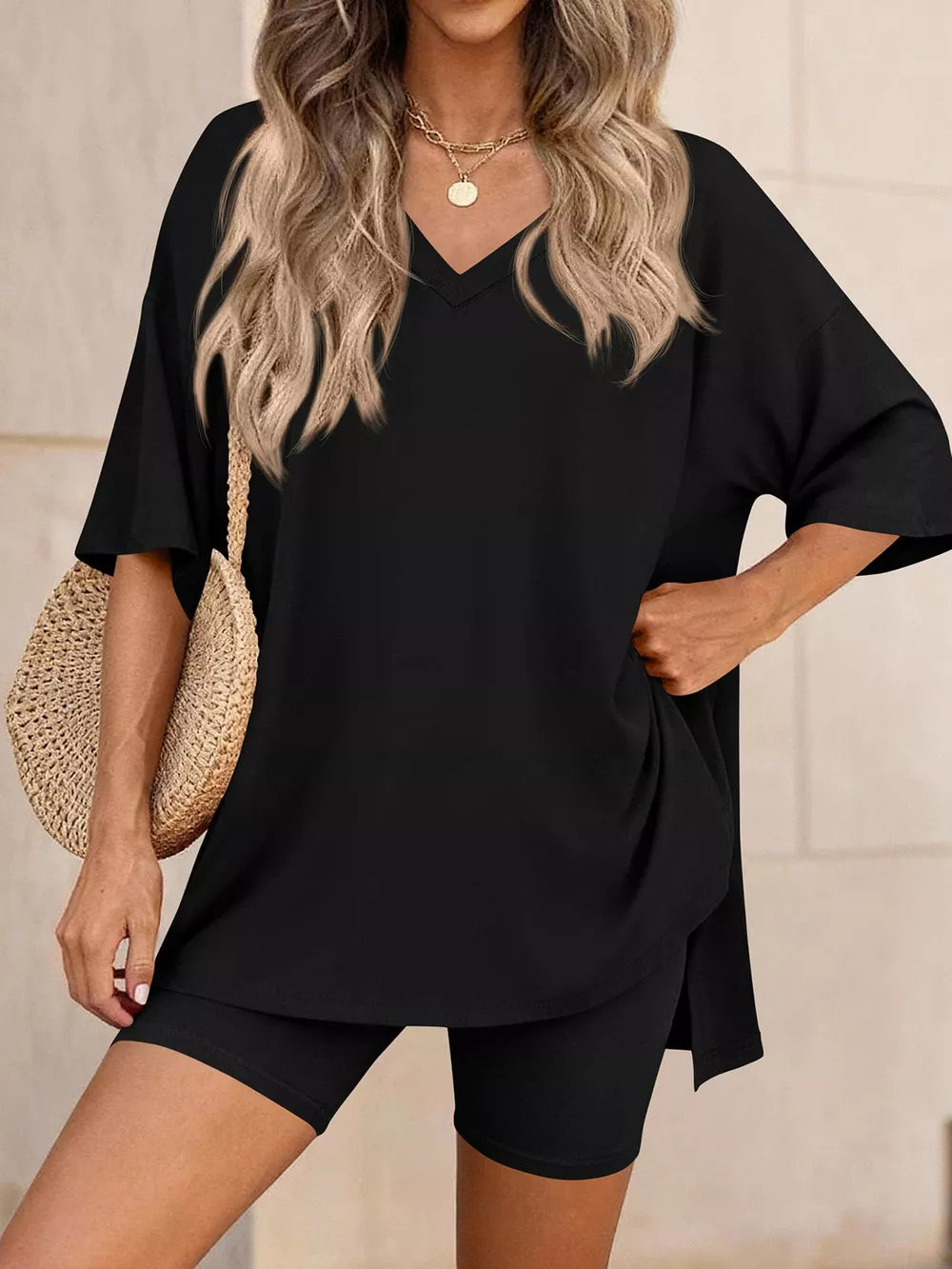 Black V-neck two-piece set with relaxed fit top and biker shorts, styled with a straw bag.