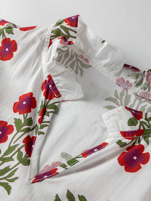 V-neck mini dress in white cotton with red floral print and ruffled collar detail.