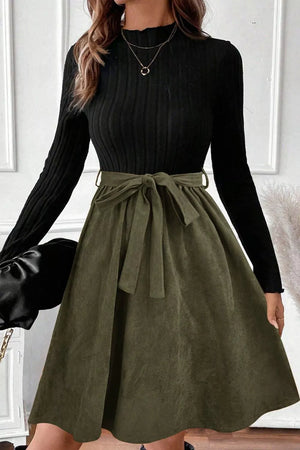 Black ribbed mock neck top with olive green A-line skirt and tie belt