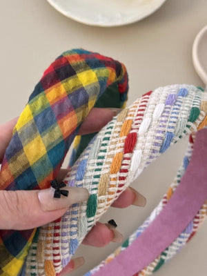 Plaid and multi-colored woven padded headbands with textured fabric and a small bow detail.