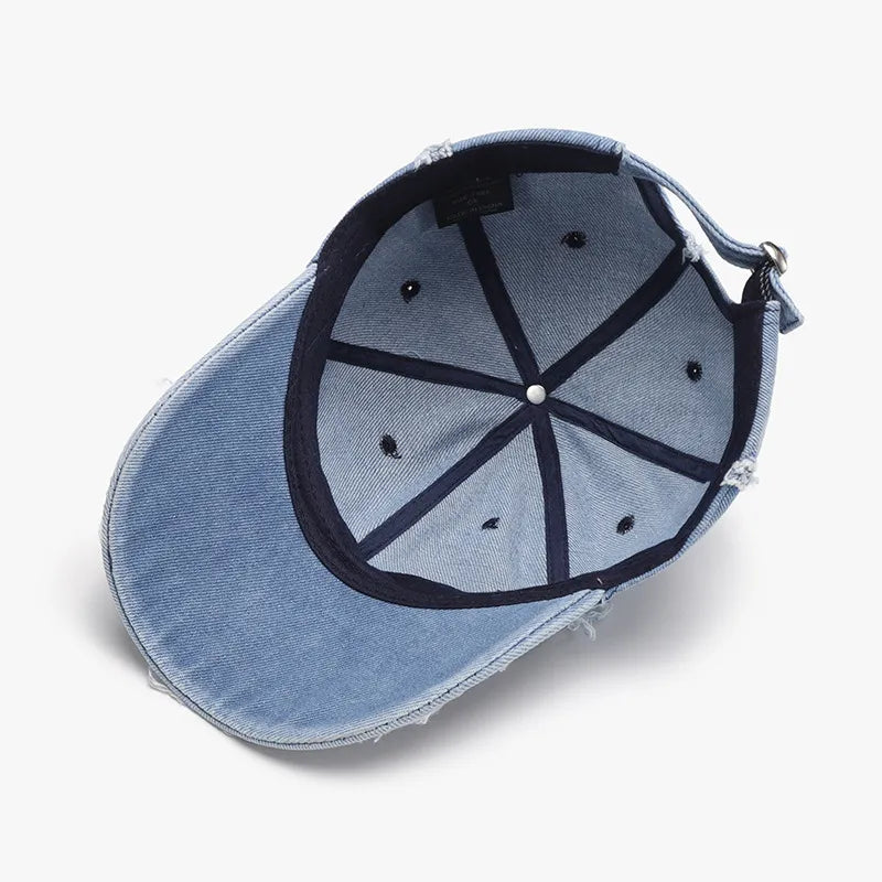 Distressed denim baseball cap in light wash with frayed edges and adjustable strap.