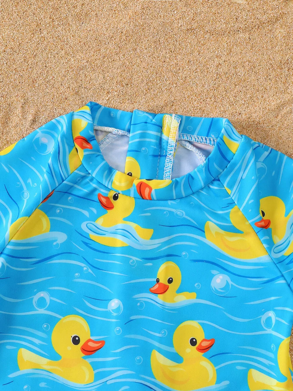 Baby swimsuit with yellow ducks on blue water pattern, long sleeves, and zipper closure.