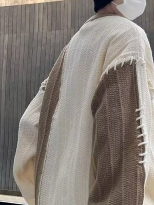 Oversized white sweater with khaki color block sleeves and decorative stitching detail.