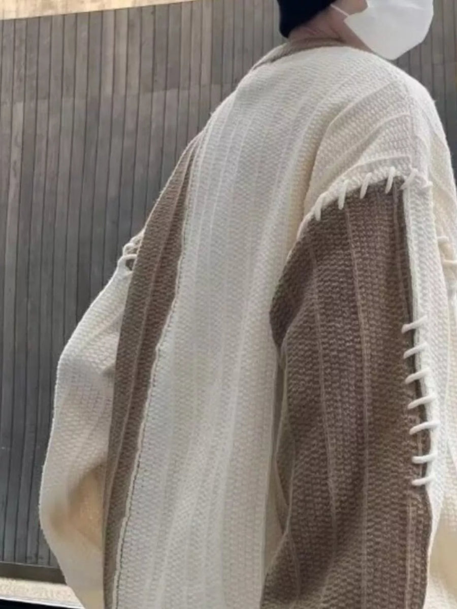 Oversized white sweater with khaki color block sleeves and decorative stitching detail.