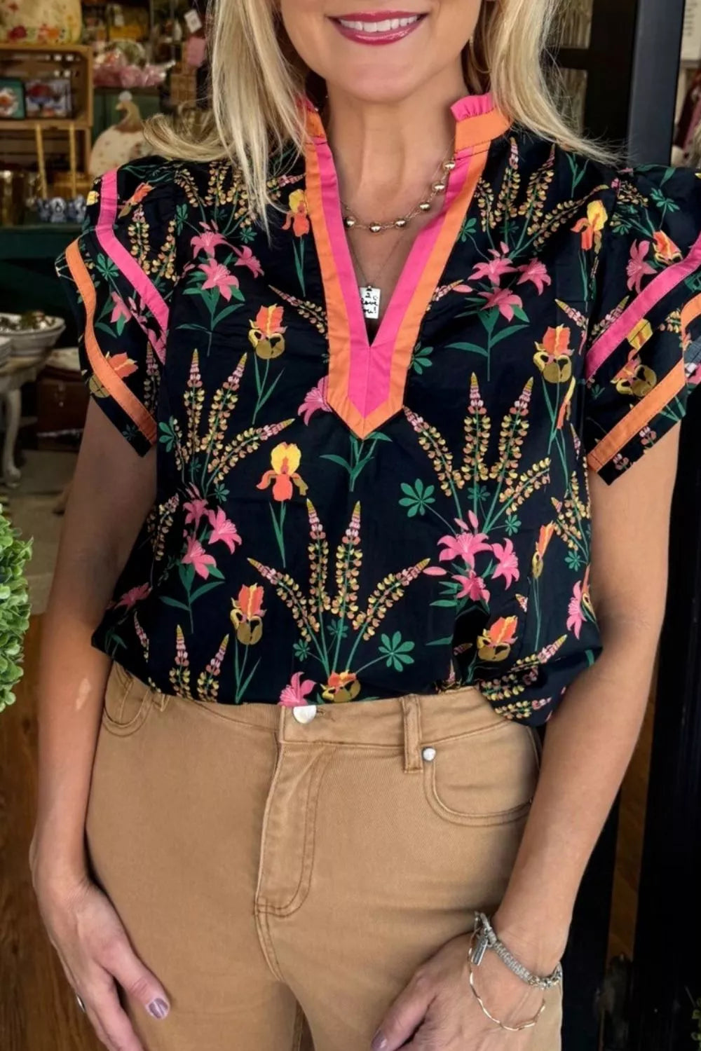 Vibrant floral print cotton blouse with contrast trim neckline and short sleeves.