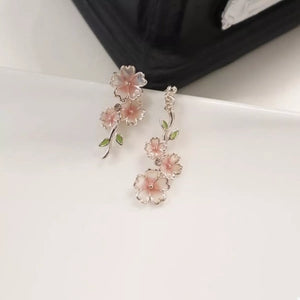 Asymmetrical blush pink floral drop earrings with green leaves and silver alloy details.