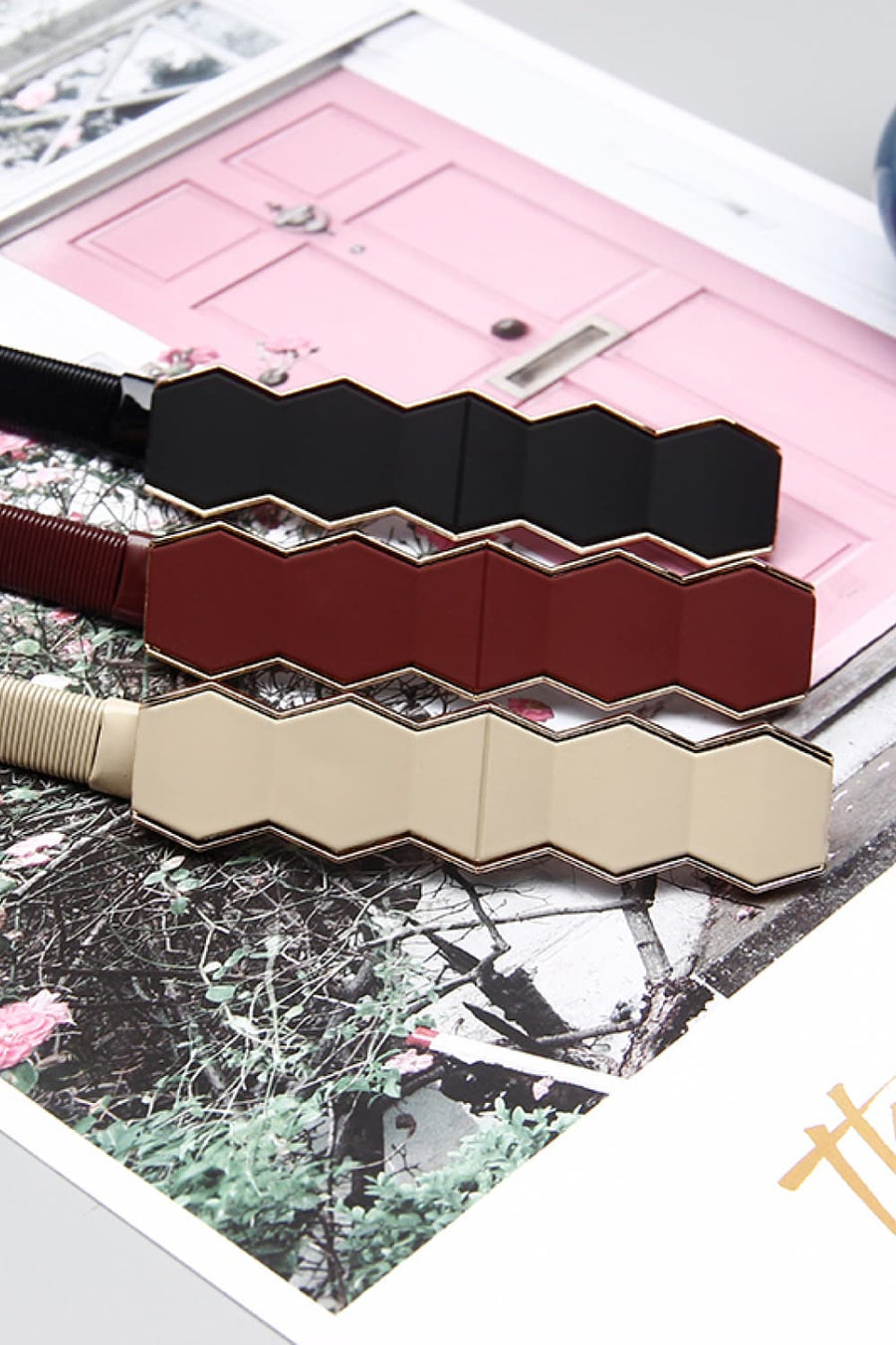 Geometric buckle waist belts in black, wine, and cream with gold trim.