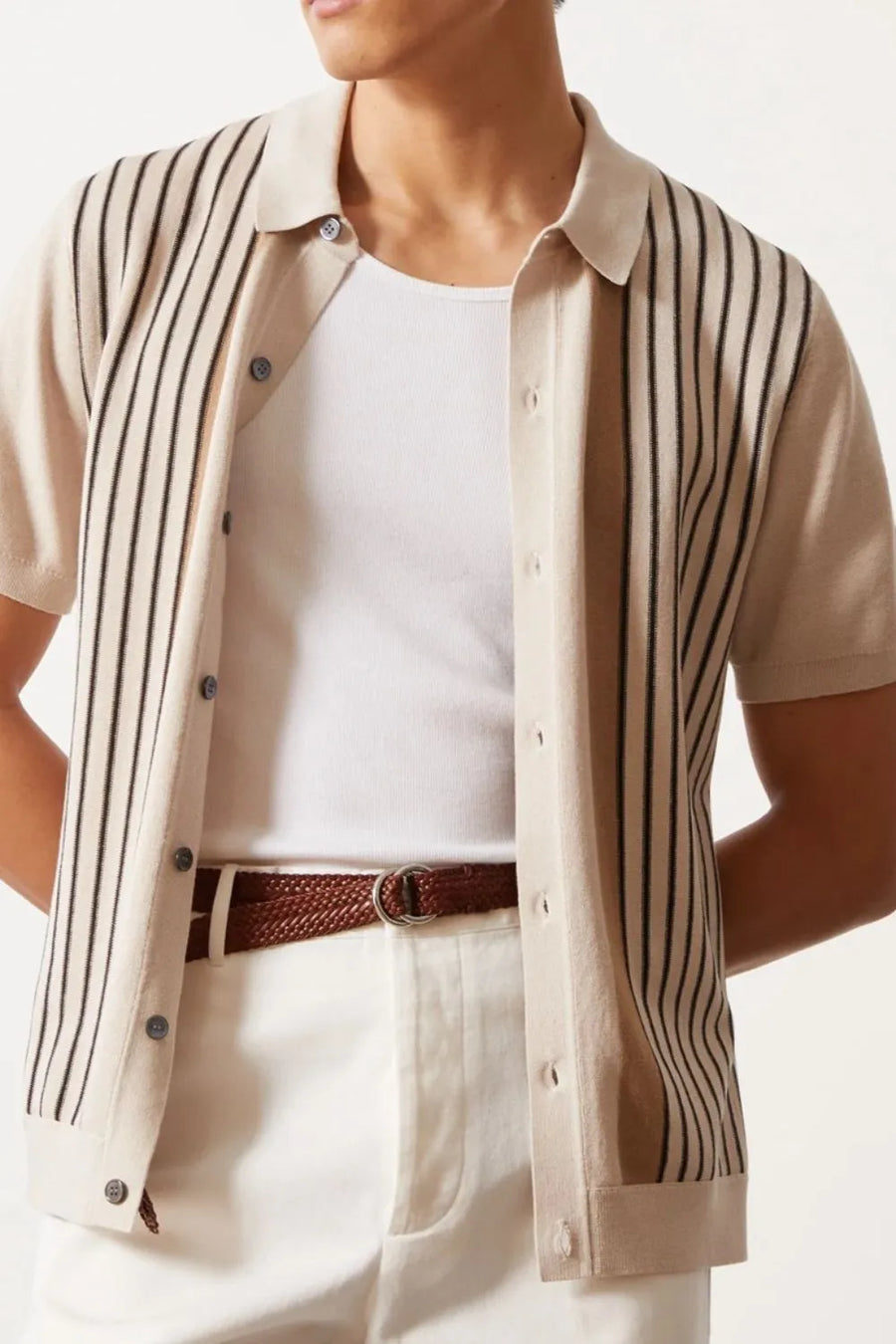 Beige knit polo shirt with vertical stripes, buttoned, short sleeves, collared.