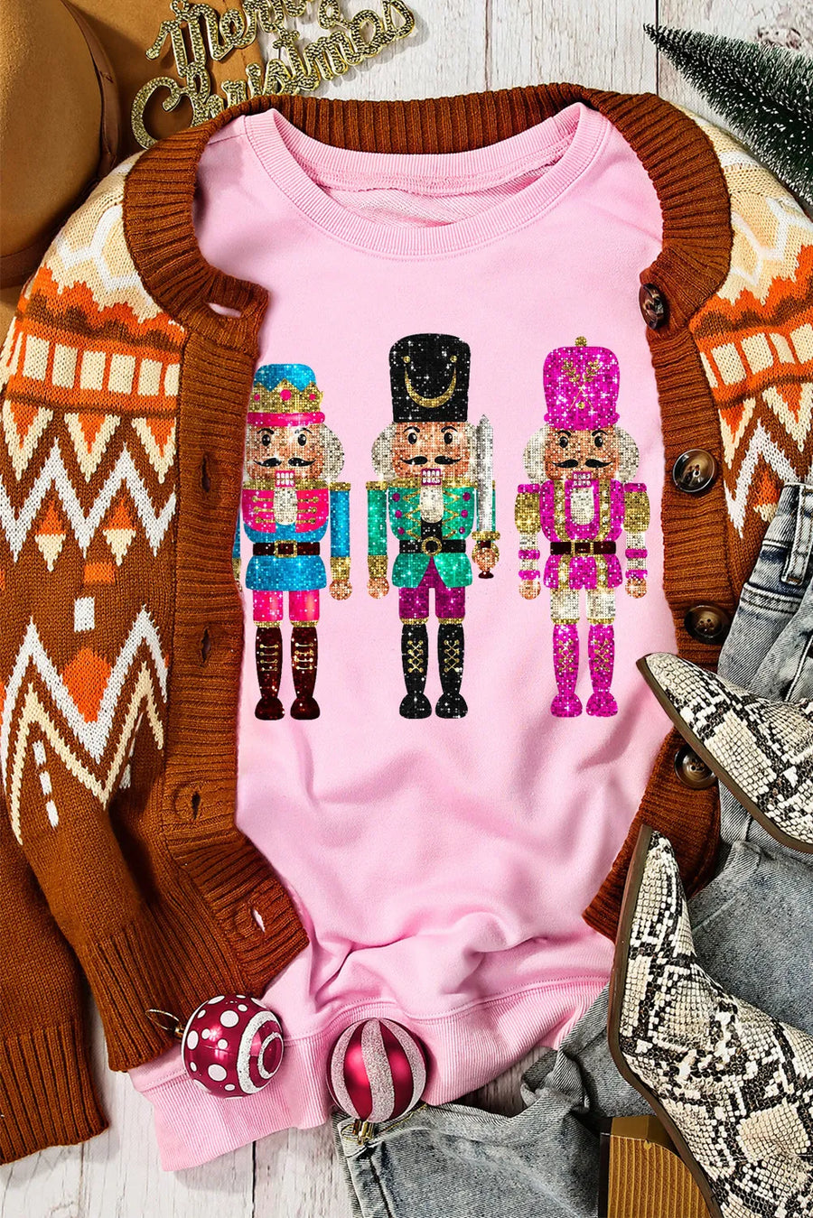 Blush pink crewneck sweatshirt with a graphic of three colorful nutcrackers.