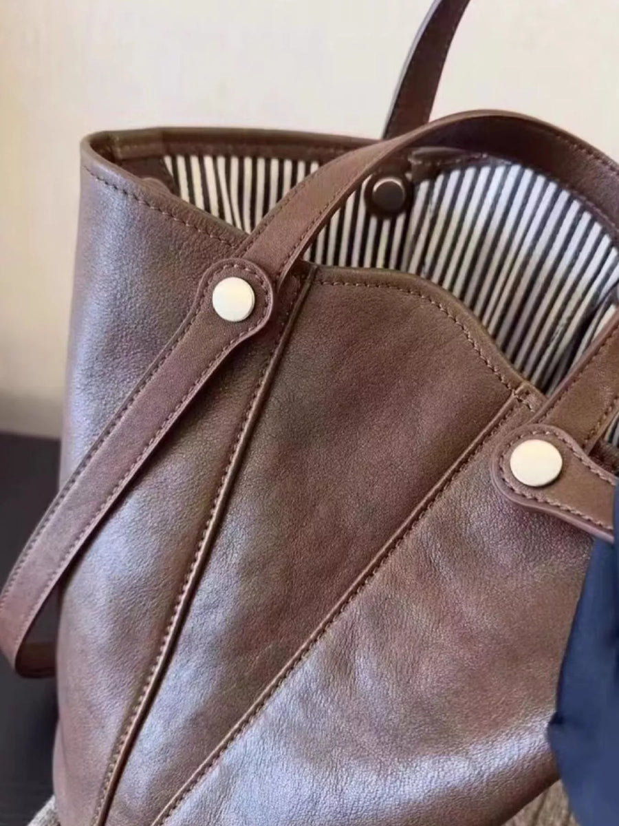 Elegant coffee brown PU leather bucket bag with striped lining and silver snap details.