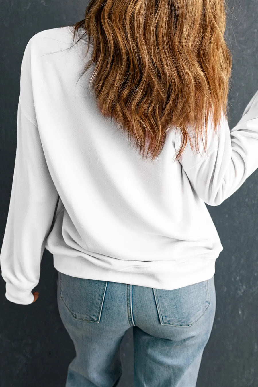 White round neck sweatshirt with long sleeves and a relaxed fit, styled with jeans.