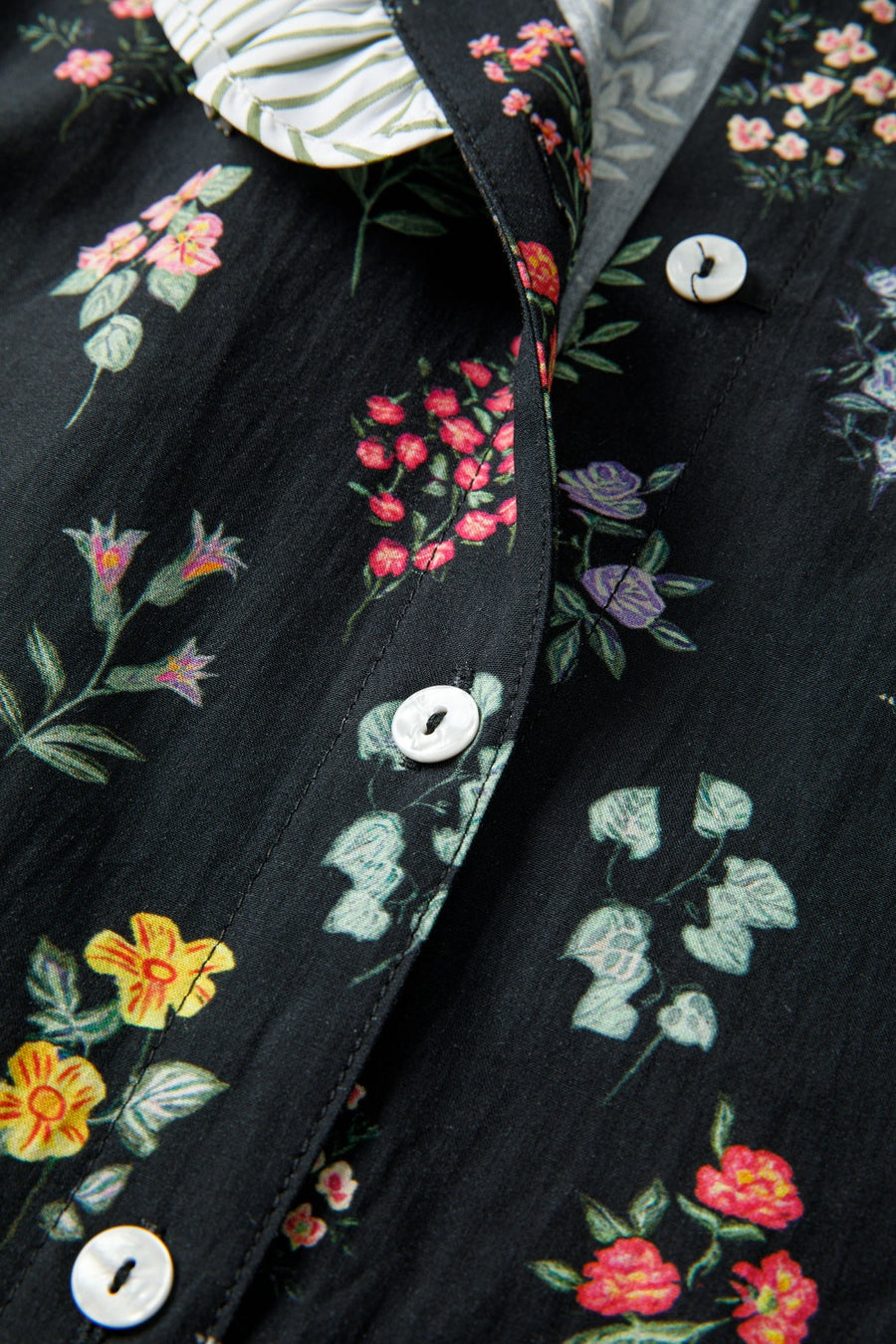 Black cotton blouse with a colorful floral print and button-down front.