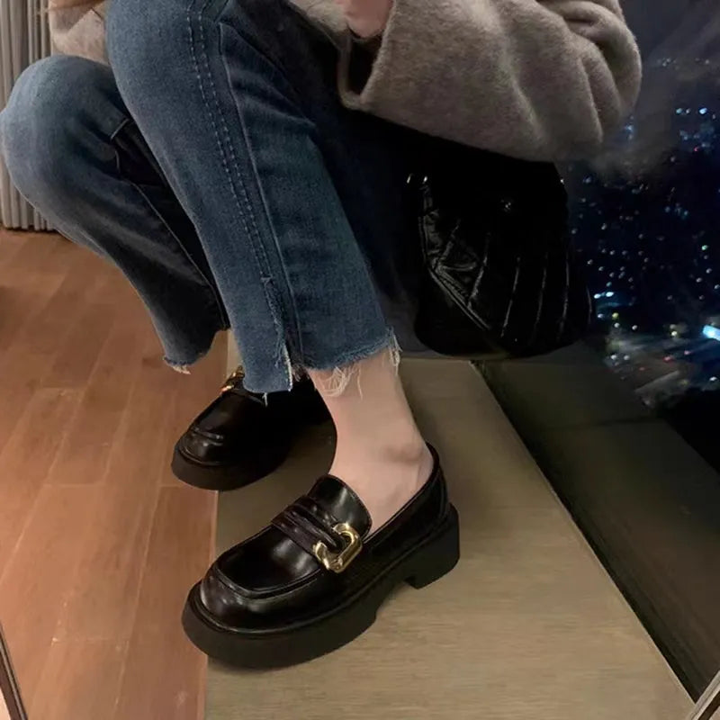 Black patent leather chunky loafers with gold buckle detail.