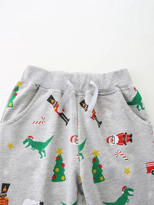 Children's gray cotton pajama pants with a fun Christmas print featuring dinosaurs, Santa, nutcrackers, and trees.