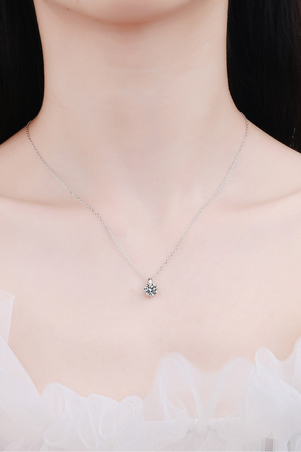 Silver solitaire moissanite pendant necklace with a delicate chain.