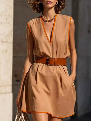 Tan sleeveless mini dress with orange trim and V-neck, cinched with a brown belt.