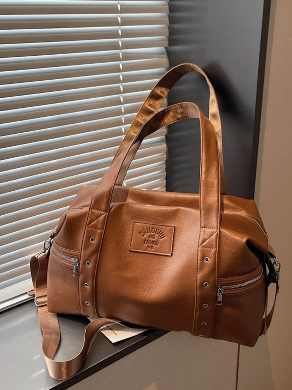 Chic medium brown pu leather shoulder bag with adjustable strap and zippered pockets.