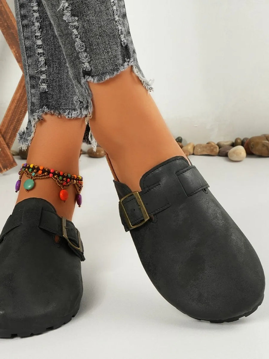 Black suede mules with buckle detail and cork sole, styled with distressed jeans and anklet.
