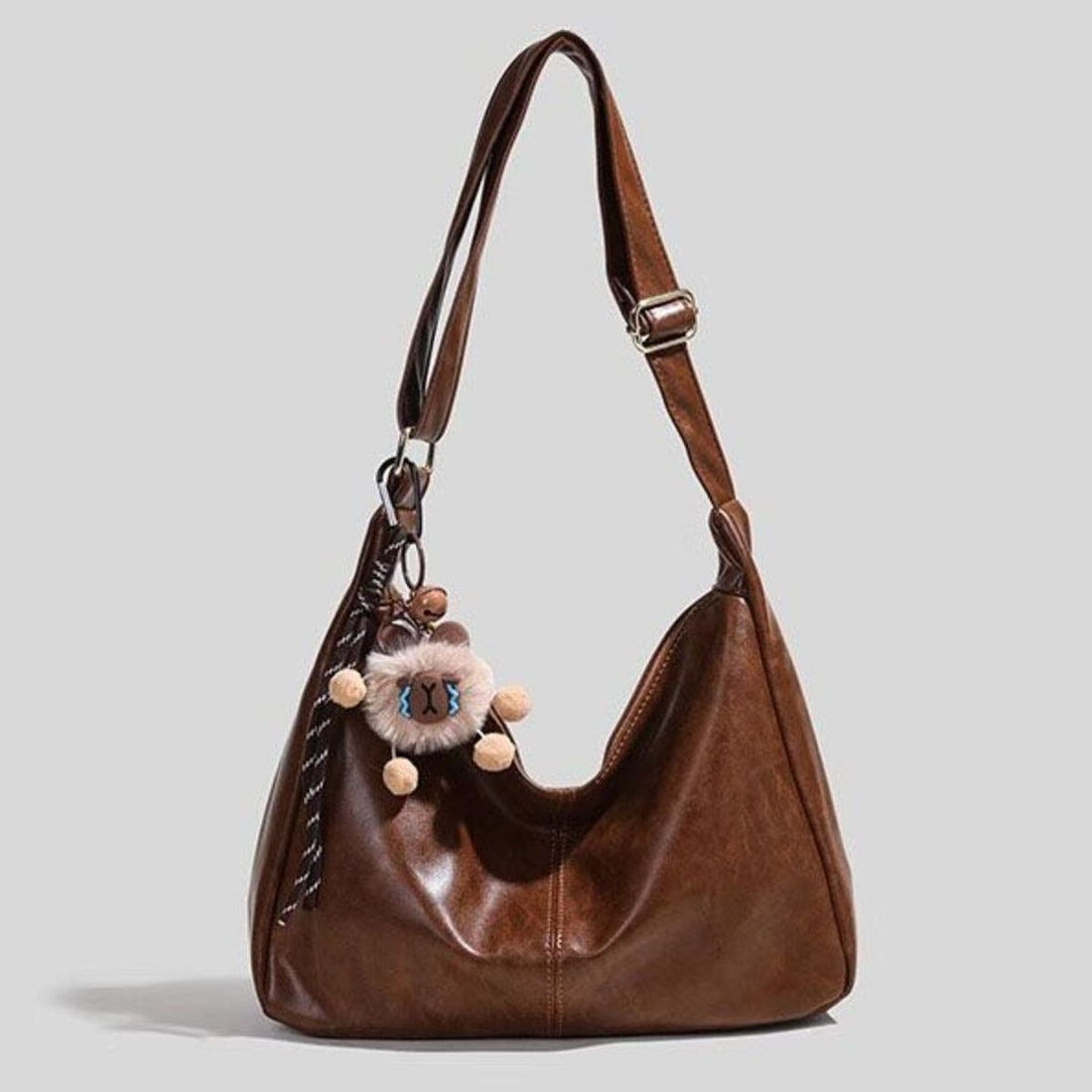 Brown vintage hobo shoulder bag with fuzzy charm and pom-poms