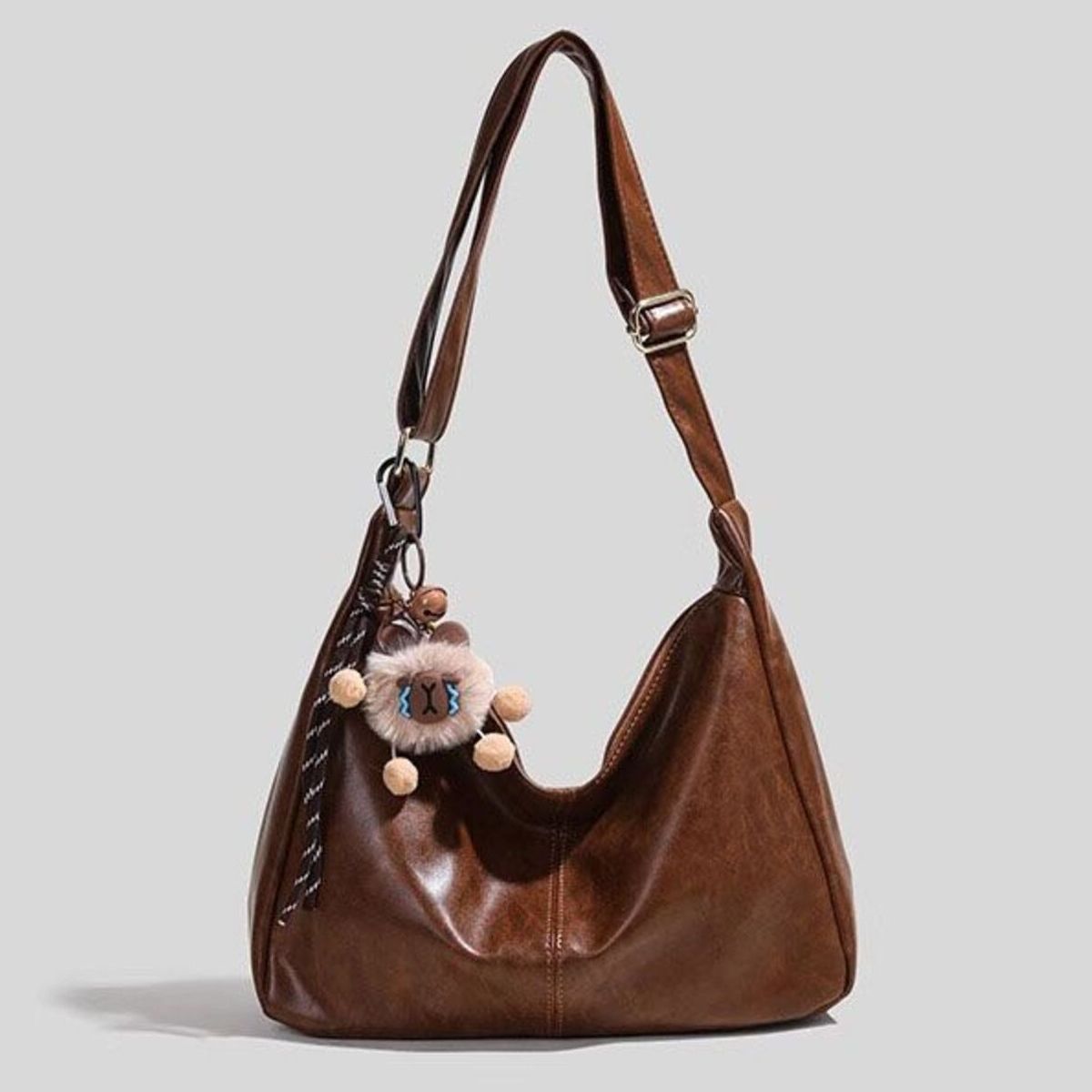 Brown vintage hobo shoulder bag with fuzzy charm and pom-poms