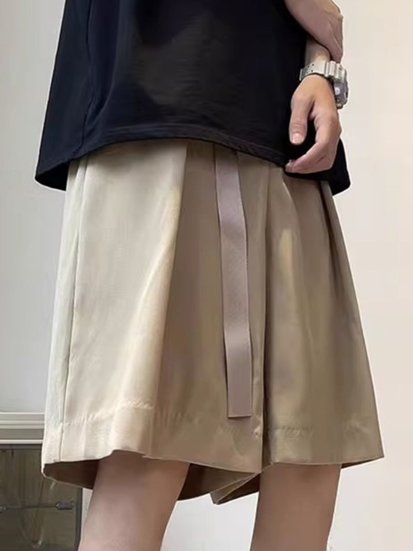 Men's khaki loose-fit casual shorts with pockets and a tonal belt detail.