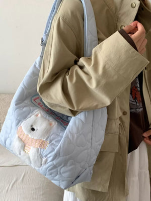 Light blue quilted crossbody bag with a white bear applique wearing a pink scarf.