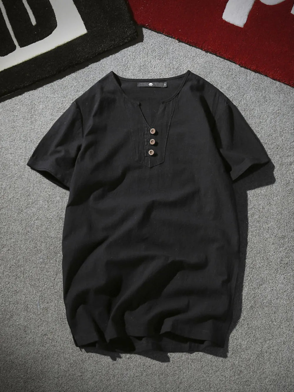 Black short sleeve buttoned shirt with V-neck and henley detail.
