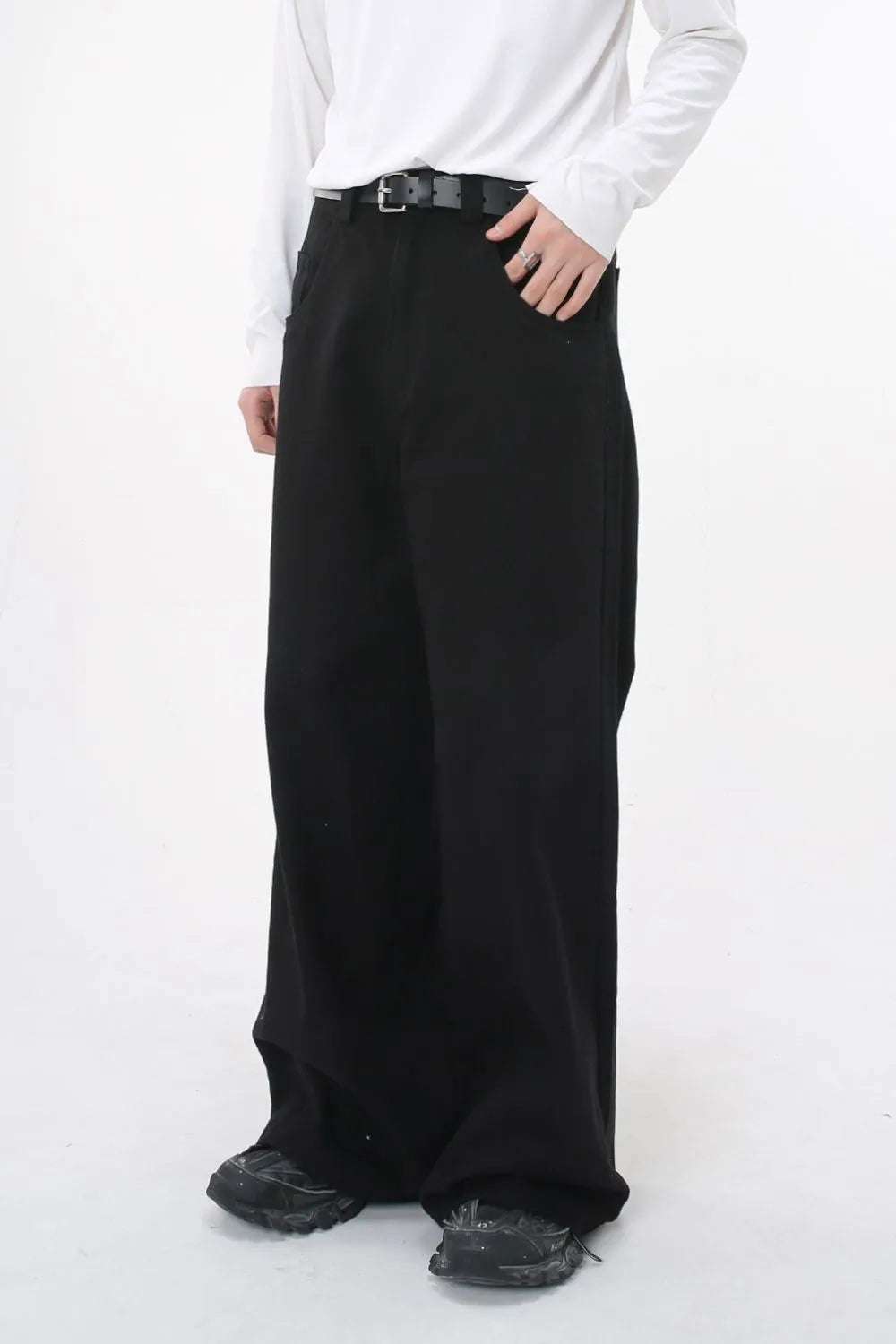 Black wide-leg denim jeans with sculpted volume and a belt, styled casually.
