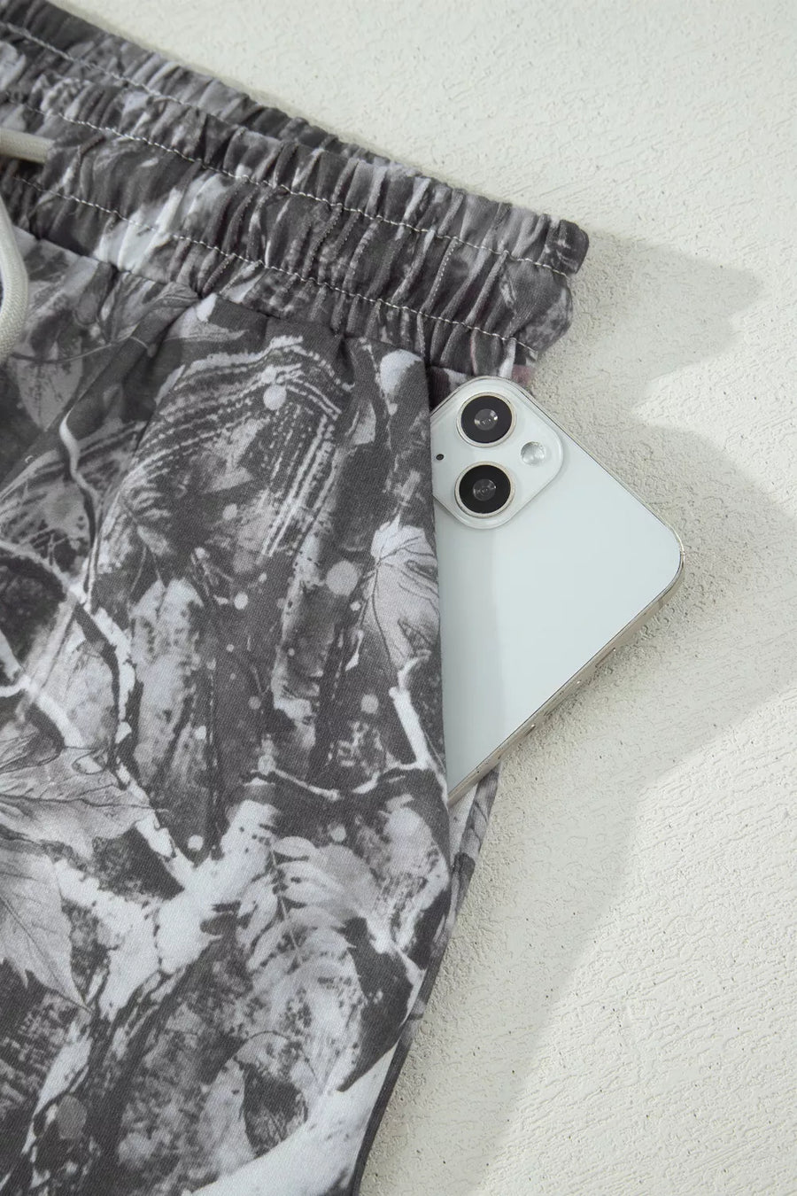 Maple leaf print elastic waist shorts with a phone in the pocket.