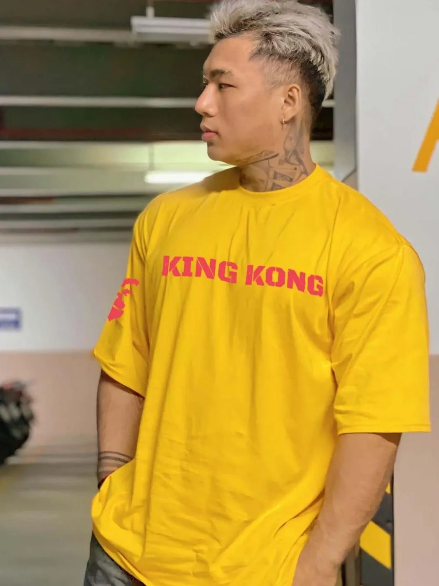 Gold oversized graphic tee with pink King Kong text and sleeve detail.