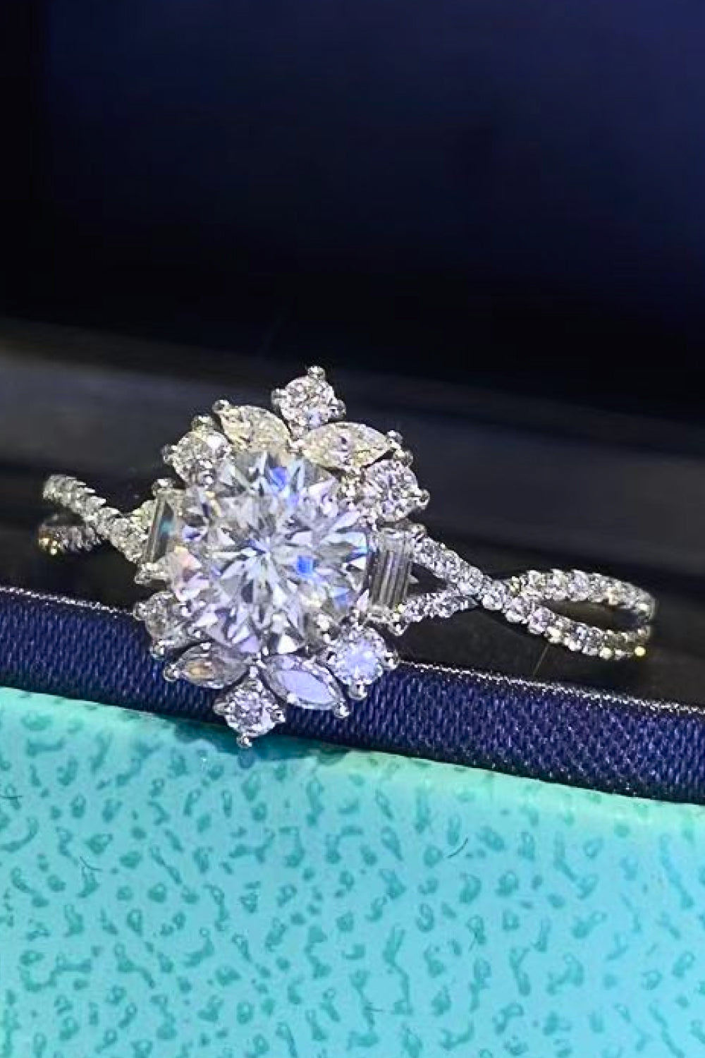 Silver floral halo ring with twisted band and round, marquise, and baguette diamonds.