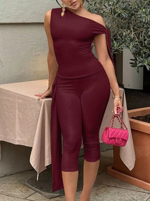 Burgundy asymmetrical one-shoulder top with capri pants ensemble, featuring a draped sleeve detail.