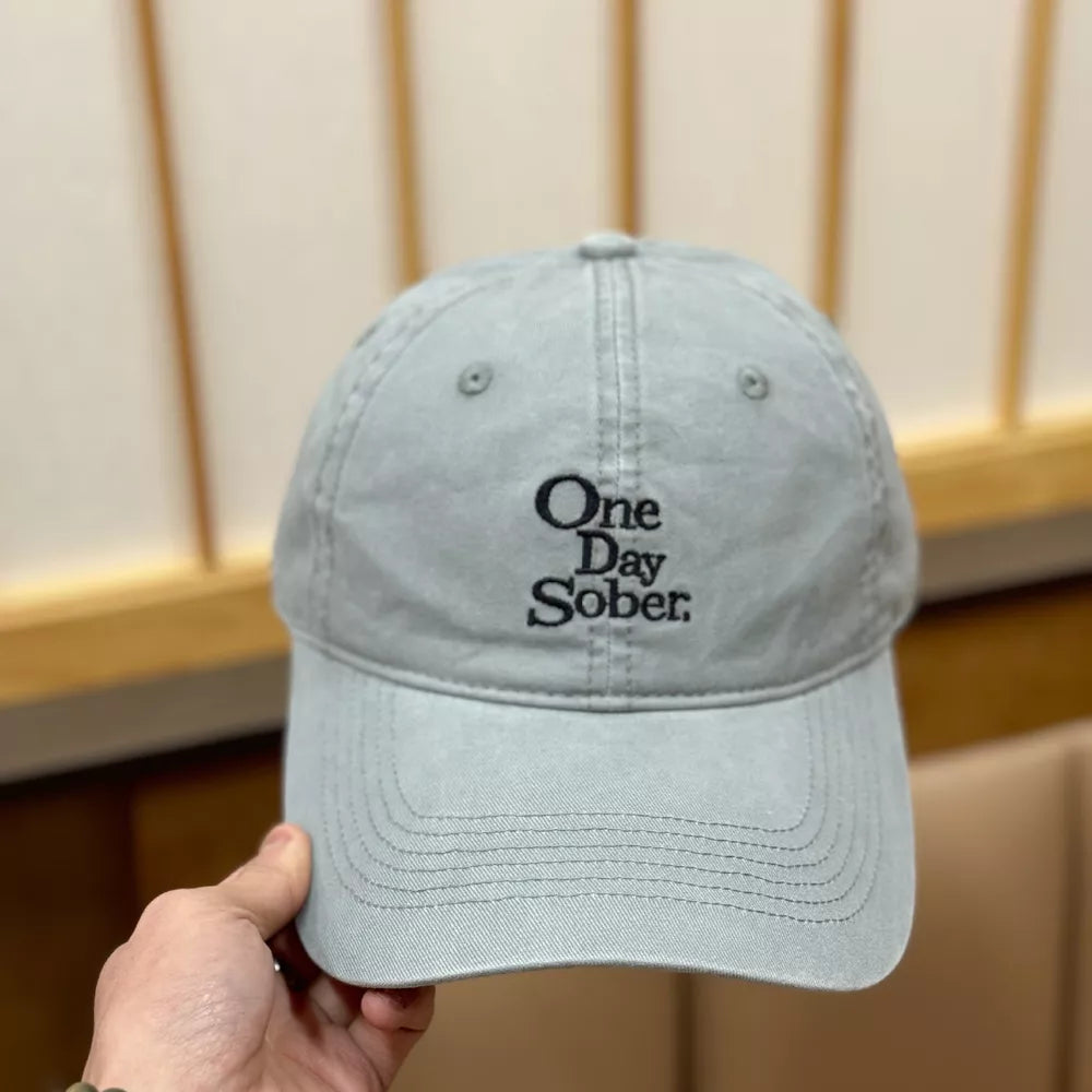 Grey baseball cap with embroidered "One Day Sober" text.