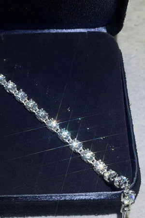 Diamond tennis bracelet in platinum with sparkling stones, presented in a dark jewelry box.