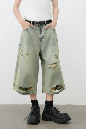Distressed culotte denim shorts in medium wash with ripped details and a wide leg.