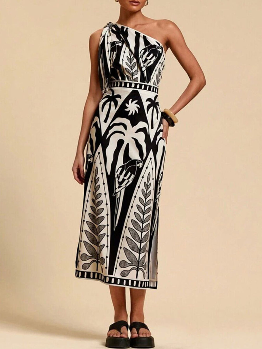 Black and white tropical print one-shoulder midi dress with defined waist and side slit.