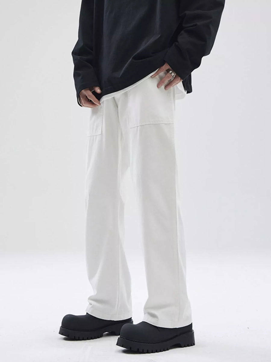 Relaxed fit white cotton chinos with patch pockets, styled with a black long sleeve shirt.