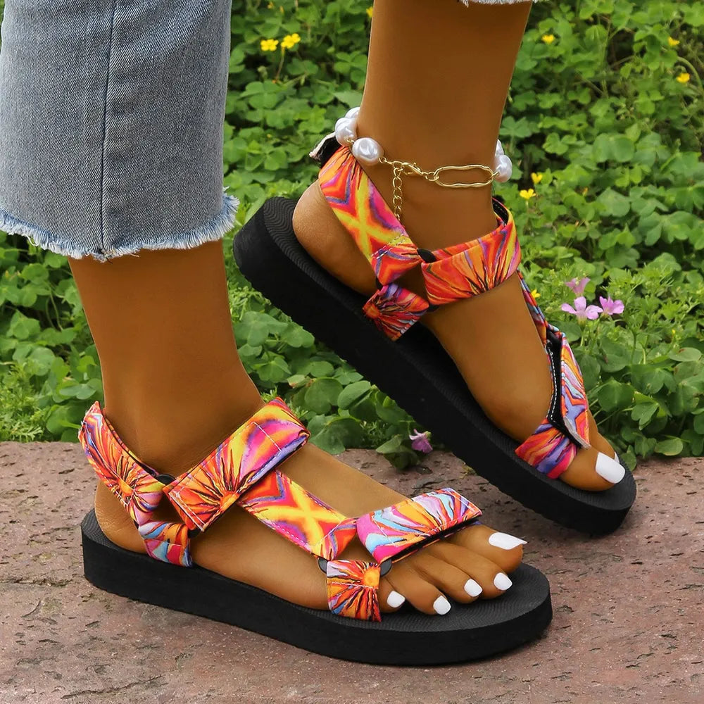 Orange camouflage platform trek sandals with adjustable straps and pearl ankle detail.
