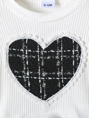 White ribbed baby top with black plaid heart applique and lace trim.