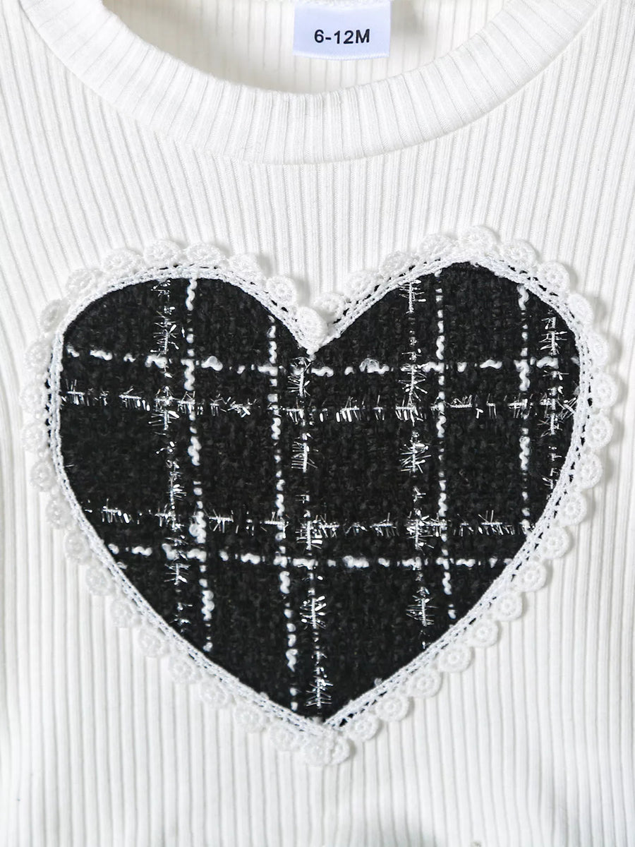 White ribbed baby top with black plaid heart applique and lace trim.