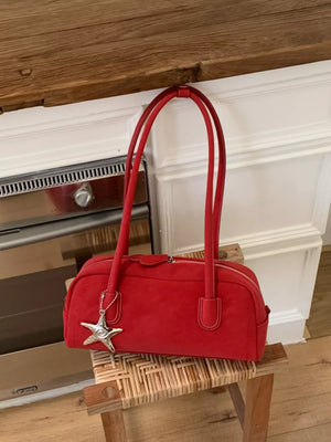Red suede shoulder bag with star charm and double handles.