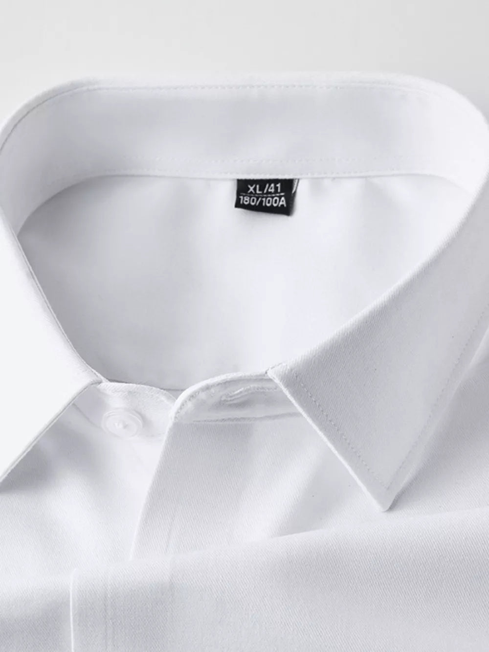 White men's long sleeve shirt with button collar detail and size tag.